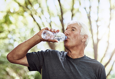 Buy stock photo Shot of a senior man drinking water while out for a run