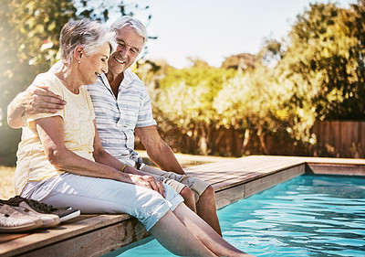 Buy stock photo Shot of a happy senior couple relaxing together by the poolside