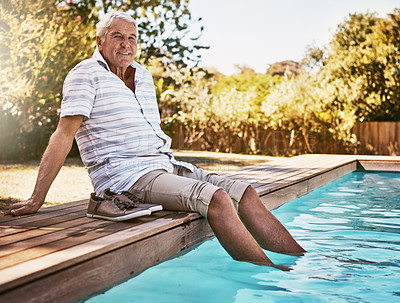 Buy stock photo Shot of a happy senior man dipping his feet in a swimming pool