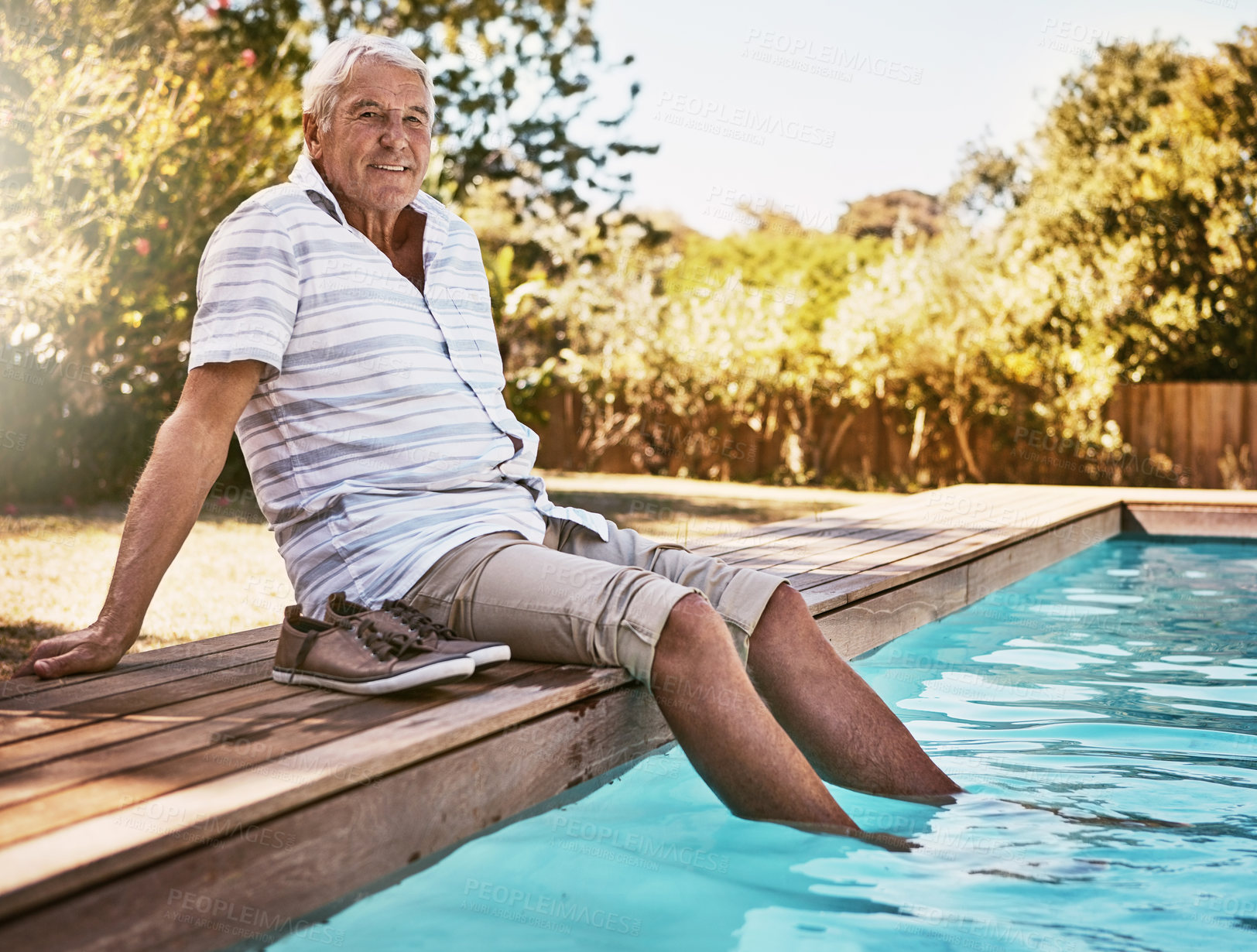 Buy stock photo Shot of a happy senior man dipping his feet in a swimming pool