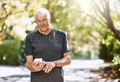 Buy stock photo Shot of a senior man texting on a cellphone while out for a run