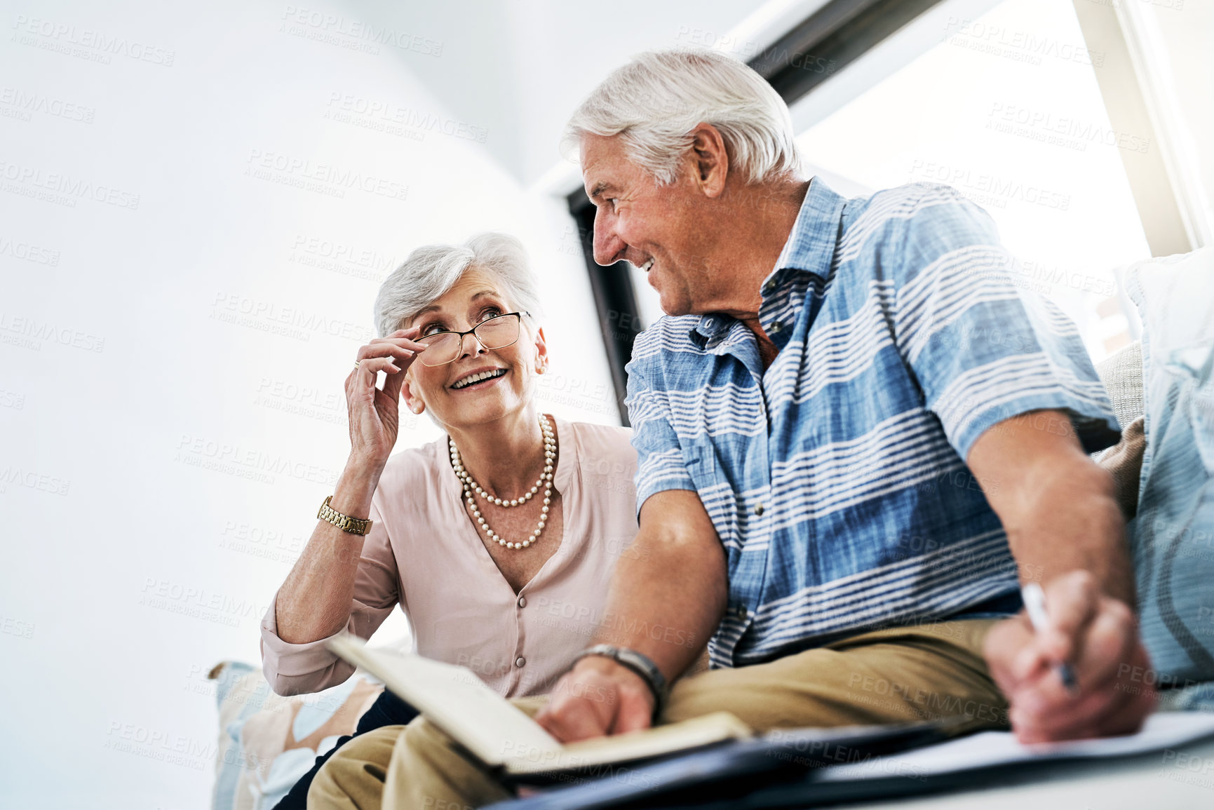 Buy stock photo Senior couple, home and happy with writing on document in sofa for grocery or shopping list for household. People, planning and budgeting, saving and notebook for insurance and asset management 