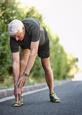 Buy stock photo Shot of a senior man warming up before a run outside