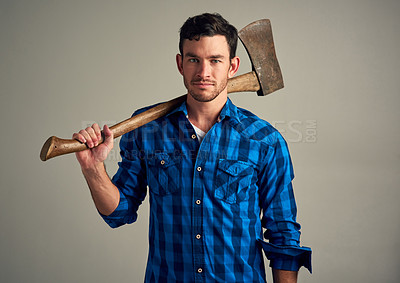 Buy stock photo Studio shot of a young male lumberjack holding an axe against a grey background