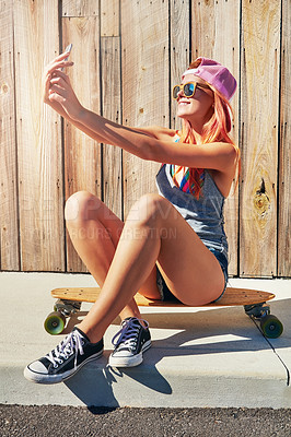 Buy stock photo Shot of a young woman taking a selfie while sitting on her skateboard