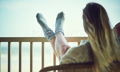 Buy stock photo Rearview shot of a woman relaxing with her feet up on the balcony