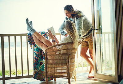 Buy stock photo Shot of a young couple reading a book together while relaxing on the balcony