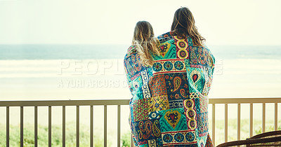 Buy stock photo Shot of a young couple wrapped in a blanket on the balcony