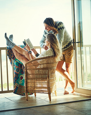 Buy stock photo Shot of a young couple reading a book together while relaxing on the balcony