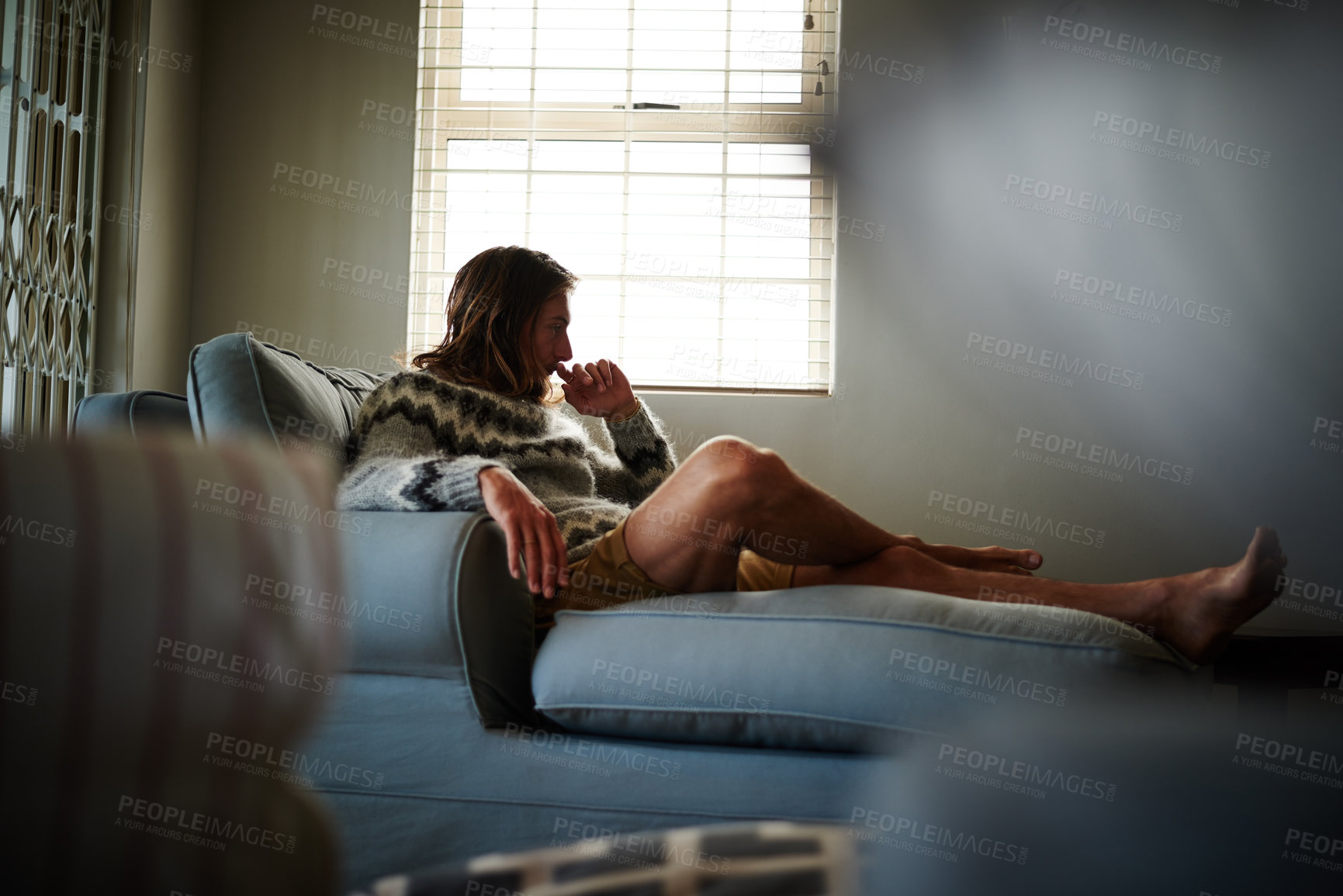 Buy stock photo Full length shot of a young man sitting on his sofa at home