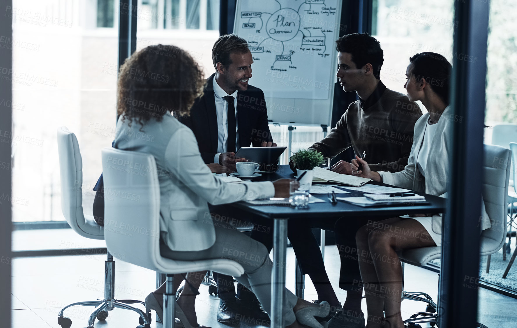 Buy stock photo Shot of a group of corporate businesspeople looking at a tablet together during a meeting in the boardroom