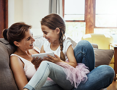 Buy stock photo Shot of a little girl using a cellphone while bonding with her mother at home