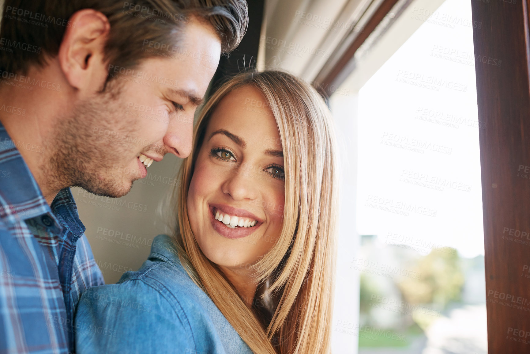 Buy stock photo Cropped shot of an affectionate young couple standing at a window in their home