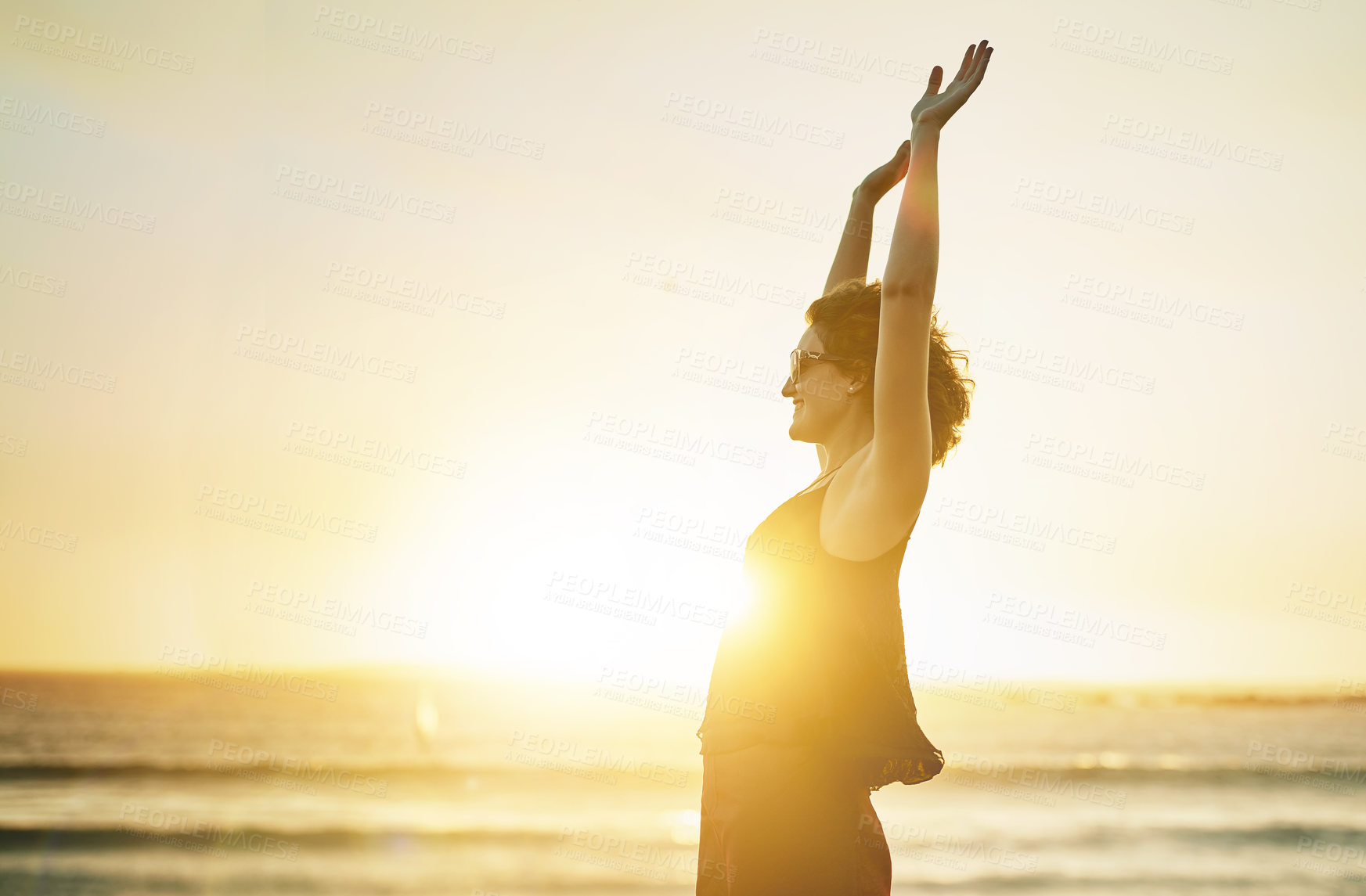 Buy stock photo Hands up, sunset and woman at beach on holiday and journey with wellness and freedom. Flare, profile and female person with arms raised, peace and light on vacation and adventure at seaside shoreline