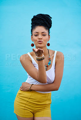 Buy stock photo Portrait of a trendy young woman blowing kisses against a blue background