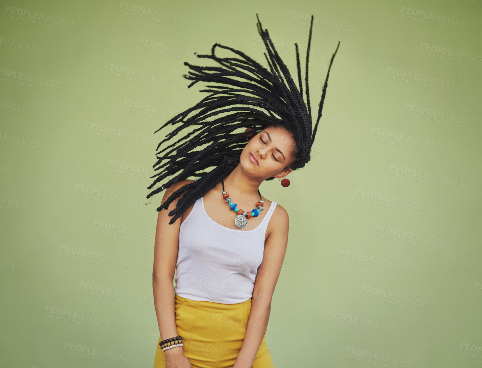 Buy stock photo Shot of an attractive young woman tossing her hair against a green background