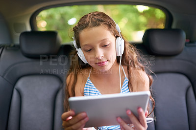 Buy stock photo Technology, young girl in car with tablet and headphones while travelling. Social media or streaming, internet connectivity and child on road trip on vacation in vehicle with digital or mobile device