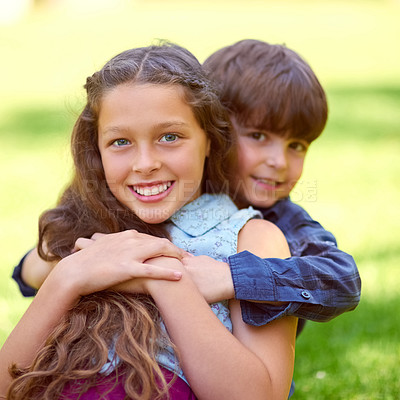Buy stock photo Portrait of a young boy embracing his sister while sitting on the grass outside