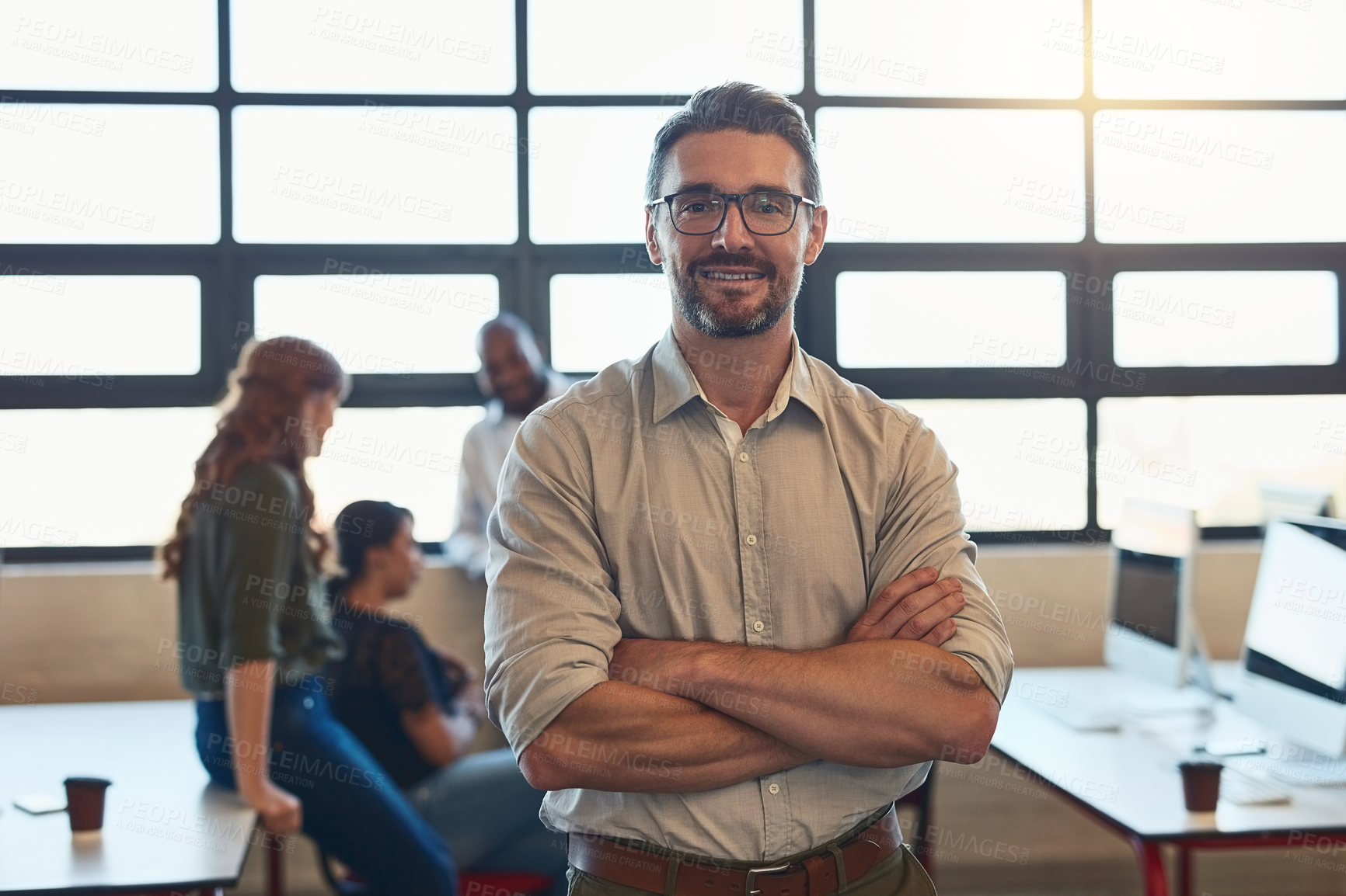 Buy stock photo Shot of a designer standing in an office with his colleagues in the background