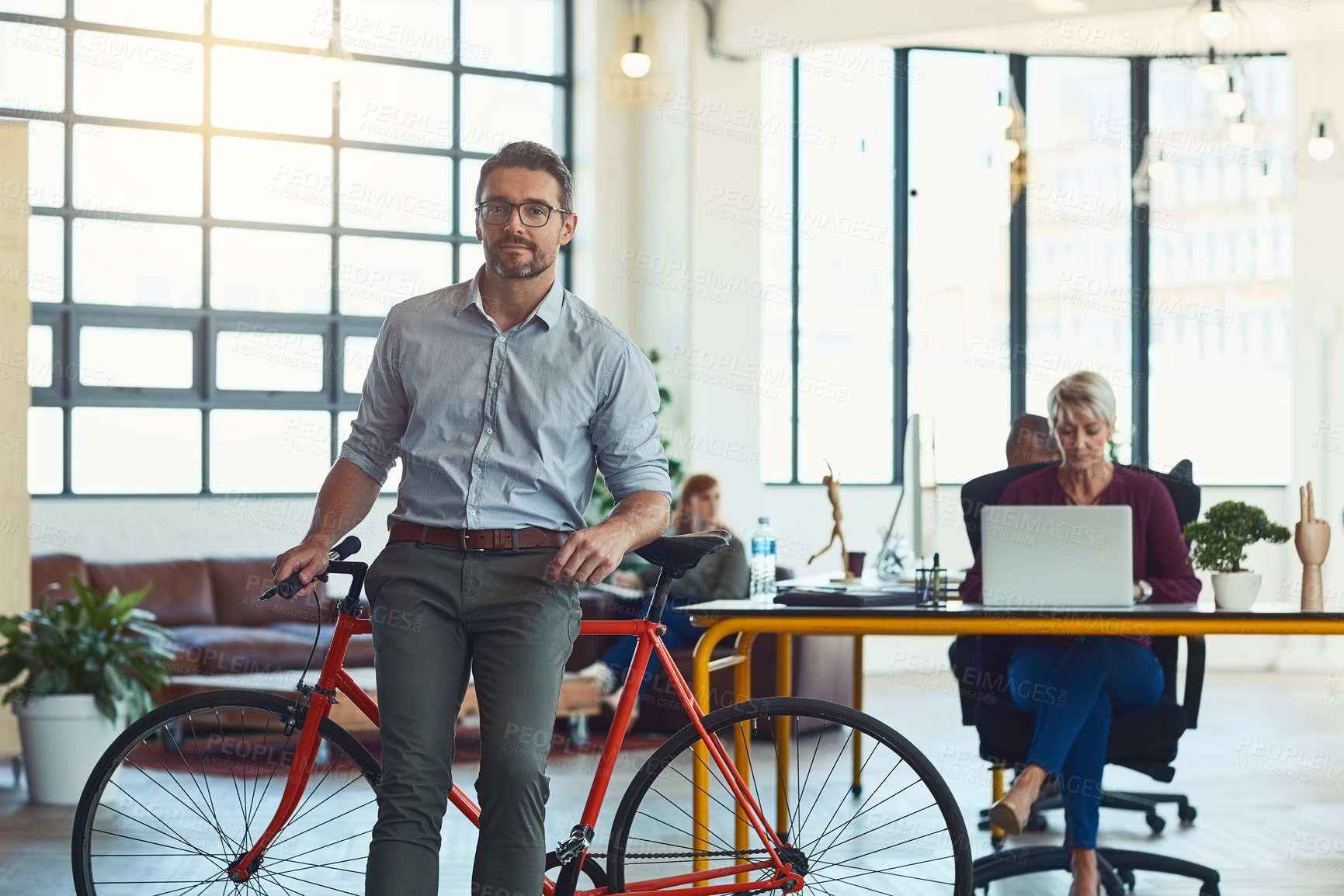 Buy stock photo Bicycle, portrait and mature man in office, relax and confident in agency, woman or technical writer on desk. Startup, entrepreneur and people in partnership, proud or editor with laptop and creative