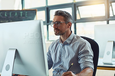Buy stock photo Shot of a mature designer working on a computer in an office