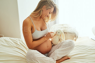 Buy stock photo Shot of a pregnant woman holding a stuffed toy while sitting on her bed