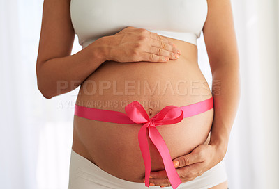 Buy stock photo Cropped shot of a woman with a pink ribbon tied around her pregnant belly