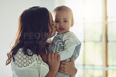 Buy stock photo Shot of a mother kissing her adorable baby boy on the cheek at home