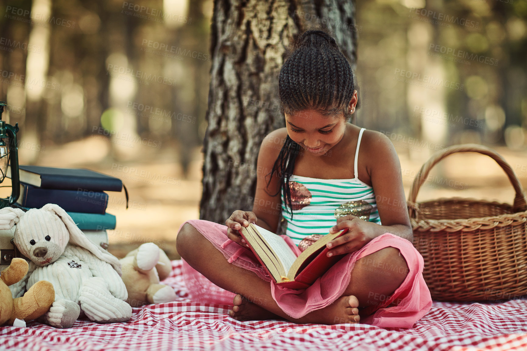 Buy stock photo Shot of a little girl reading a book with her toys in the woods