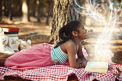 Buy stock photo Shot of a little girl reading a book with glowing pages in the woods