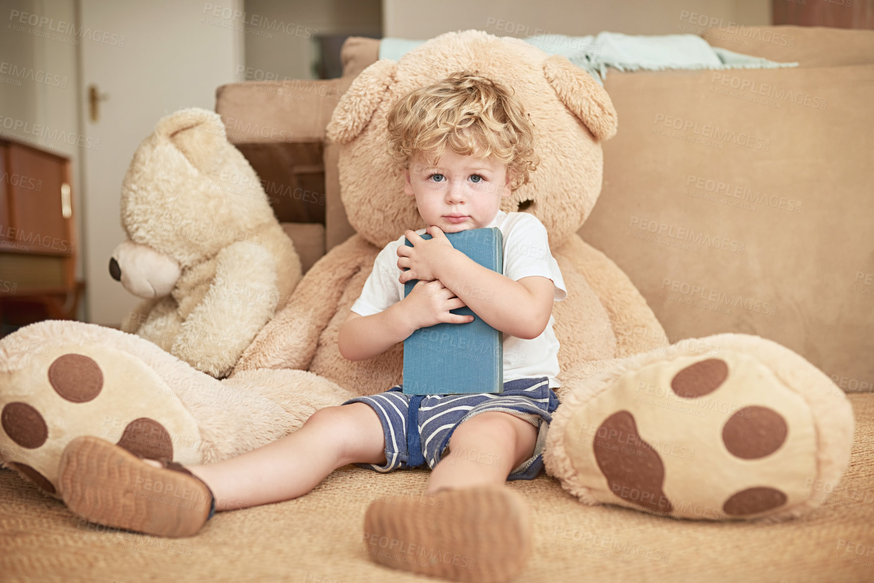 Buy stock photo Portrait of an adorable little boy reading with his teddy bear at home