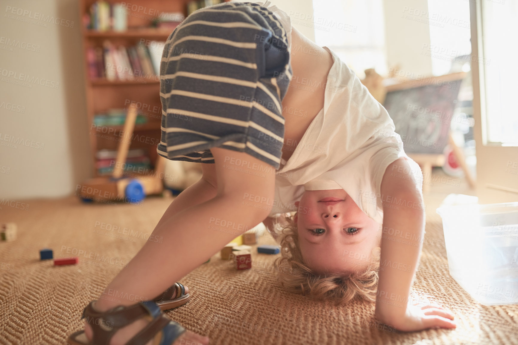 Buy stock photo Shot of an adorable little boy trying to do a handstand at home