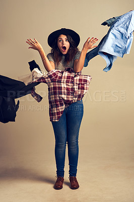 Buy stock photo Studio shot of a young woman tossing clothing against a brown background