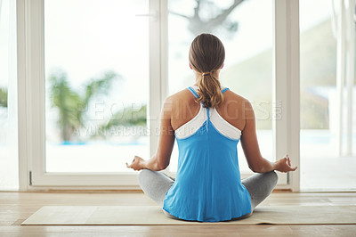 Buy stock photo Rearview shot of a young woman practicing yoga at home