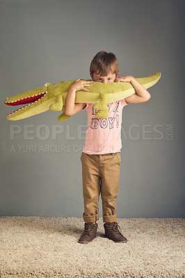 Buy stock photo Studio portrait of an adorable little boy playing with a crocodile toy against a gray background