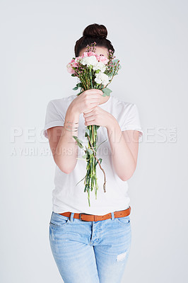 Buy stock photo Studio shot of an unrecognizable woman covering her face with flowers against a grey background