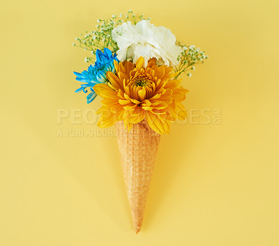 Buy stock photo Shot of a cone stuffed with flowers against a colorful background