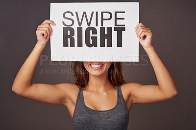 Buy stock photo Studio shot of a young woman holding a sign with swipe right printed on it against a gray background