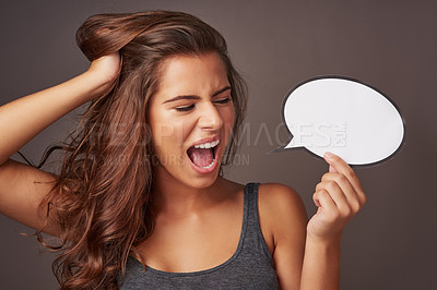 Buy stock photo Studio shot of an attractive young woman holding a blank speech bubble and shouting against a gray background