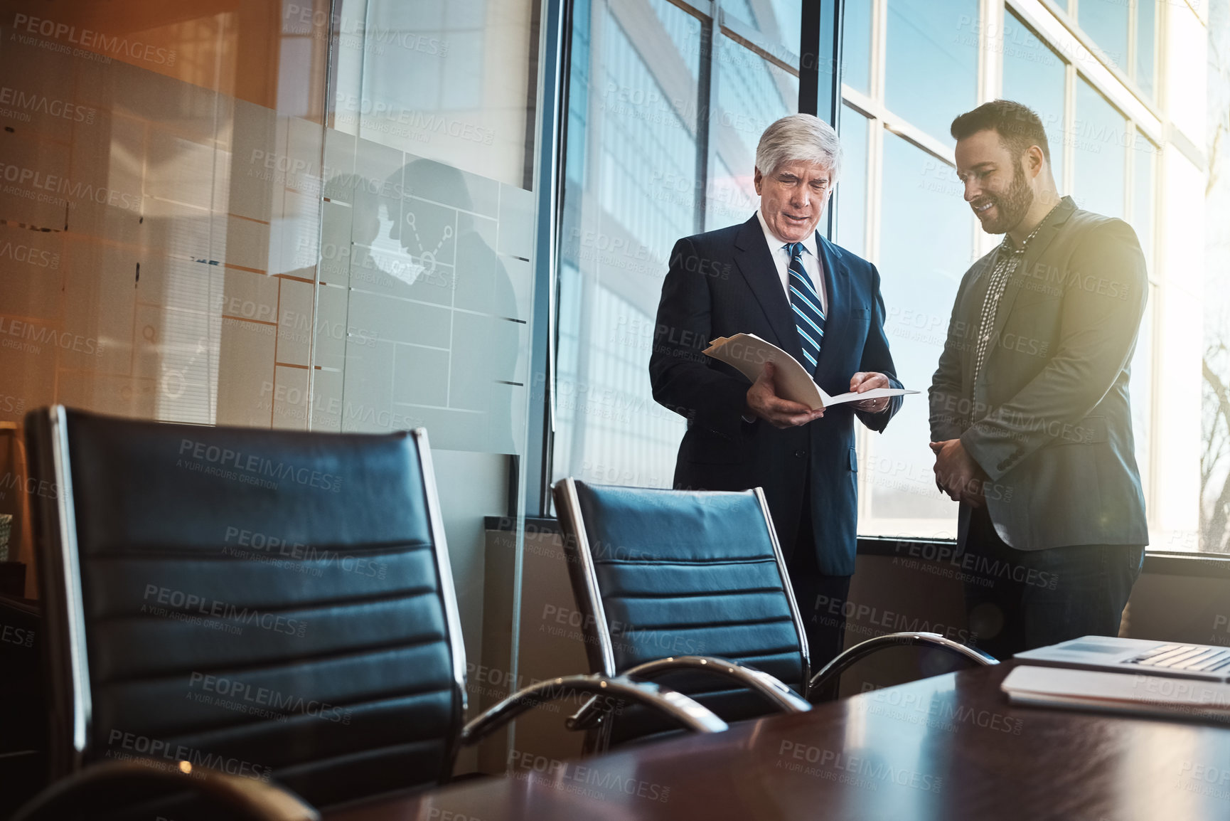 Buy stock photo Cropped shot of two businessmen looking over some paperwork in the office