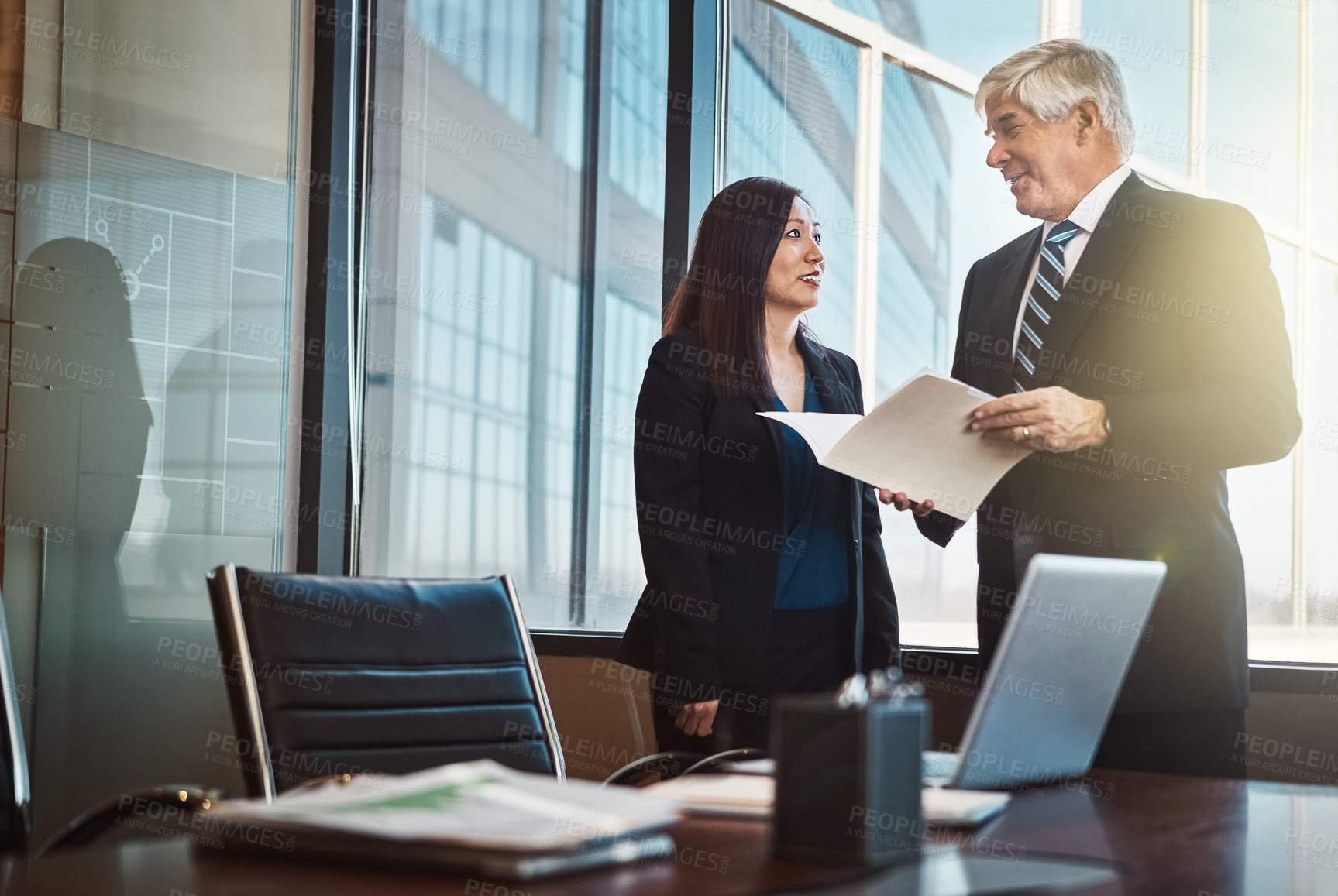 Buy stock photo Cropped shot of two mature businesspeople looking over some paperwork in an office