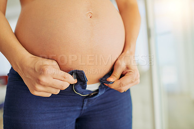 Buy stock photo Cropped shot of a pregnant woman putting on her pants at home