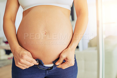 Buy stock photo Cropped shot of a pregnant woman putting on her pants at home