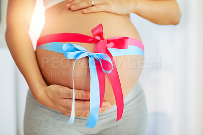 Buy stock photo Cropped shot of a pregnant woman with pink and blue ribbons tied around her belly