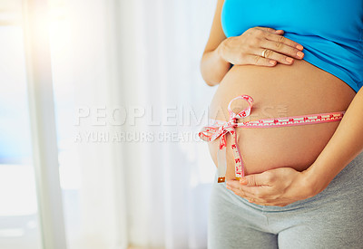 Buy stock photo Cropped shot of a pregnant woman with a tape measure tied around her belly