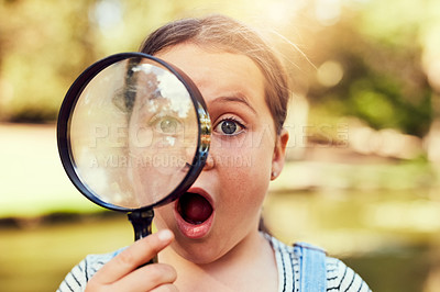 Buy stock photo Portrait of a little girl looking through a magnifying glass in amazement