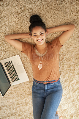 Buy stock photo Shot of a beautiful young woman lying down next to a laptop at home