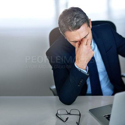 Buy stock photo Shot of an overworked businessman resting with his head in his hands in the office