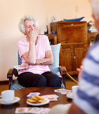 Buy stock photo Shot of a happy senior woman laughing during a card game with her friends in a retirement home