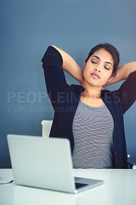 Buy stock photo Shot of a tired young businesswoman stretching while sitting at her desk